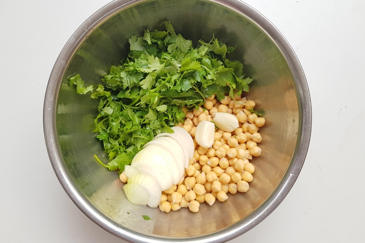 Замоченный нут и рубленая зелень в мисках для приготовления фалафеля.